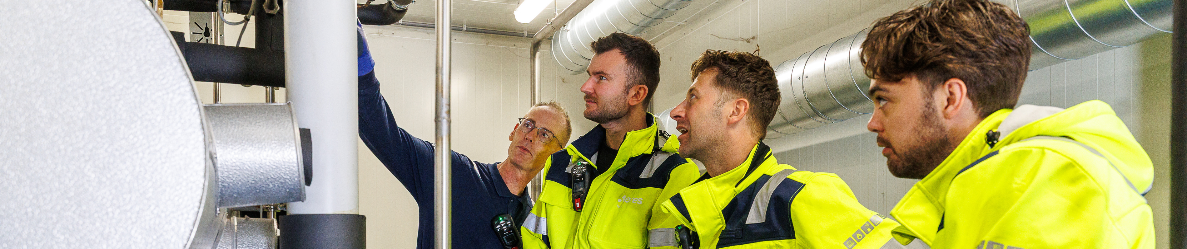 Drie cursisten krijgen uitleg bij ammoniakinstallatie