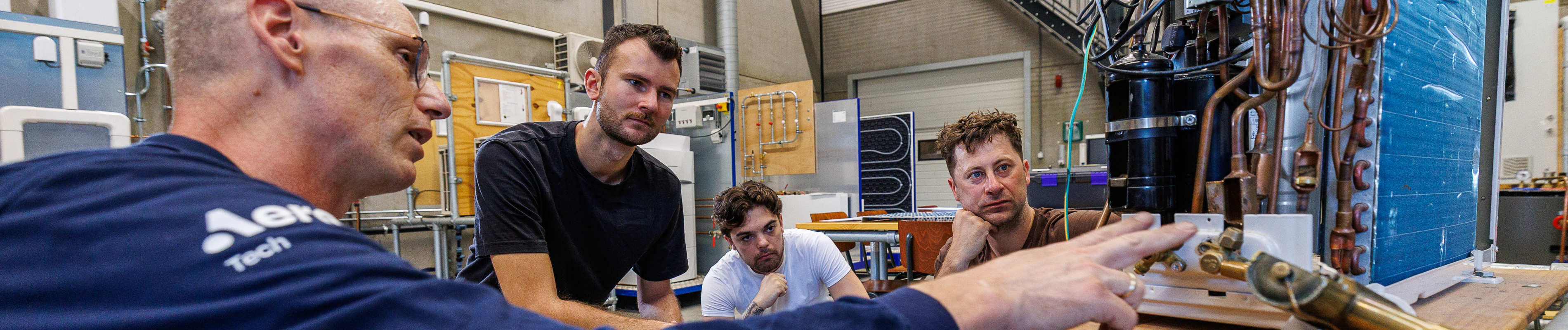 Trainer geeft uitleg bij warmtepomp