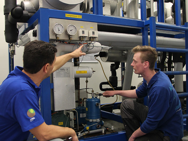 Twee mannen bekijken en wijst naar warmtepomp