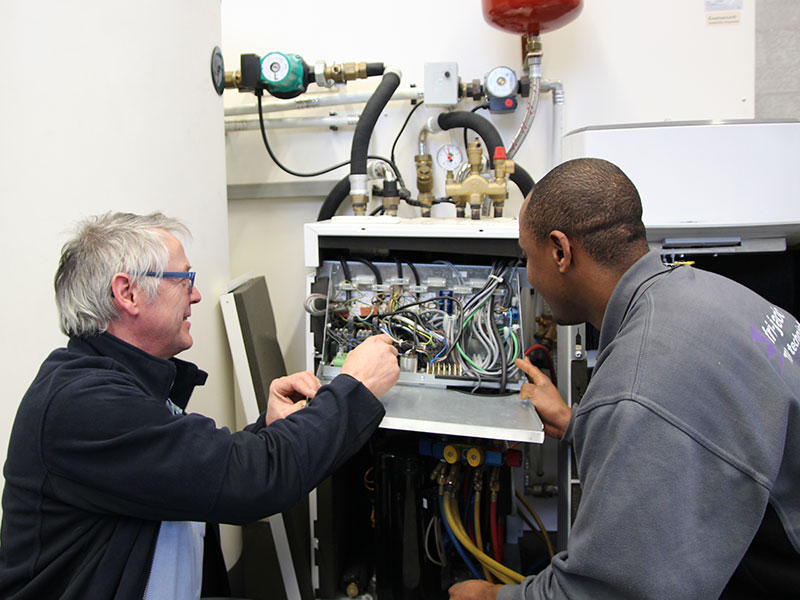 Twee mannen werken aan bedrading warmtepomp
