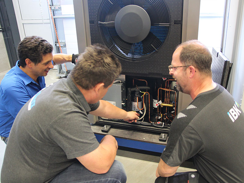 Drie mannen gehurkt bij warmtepomp